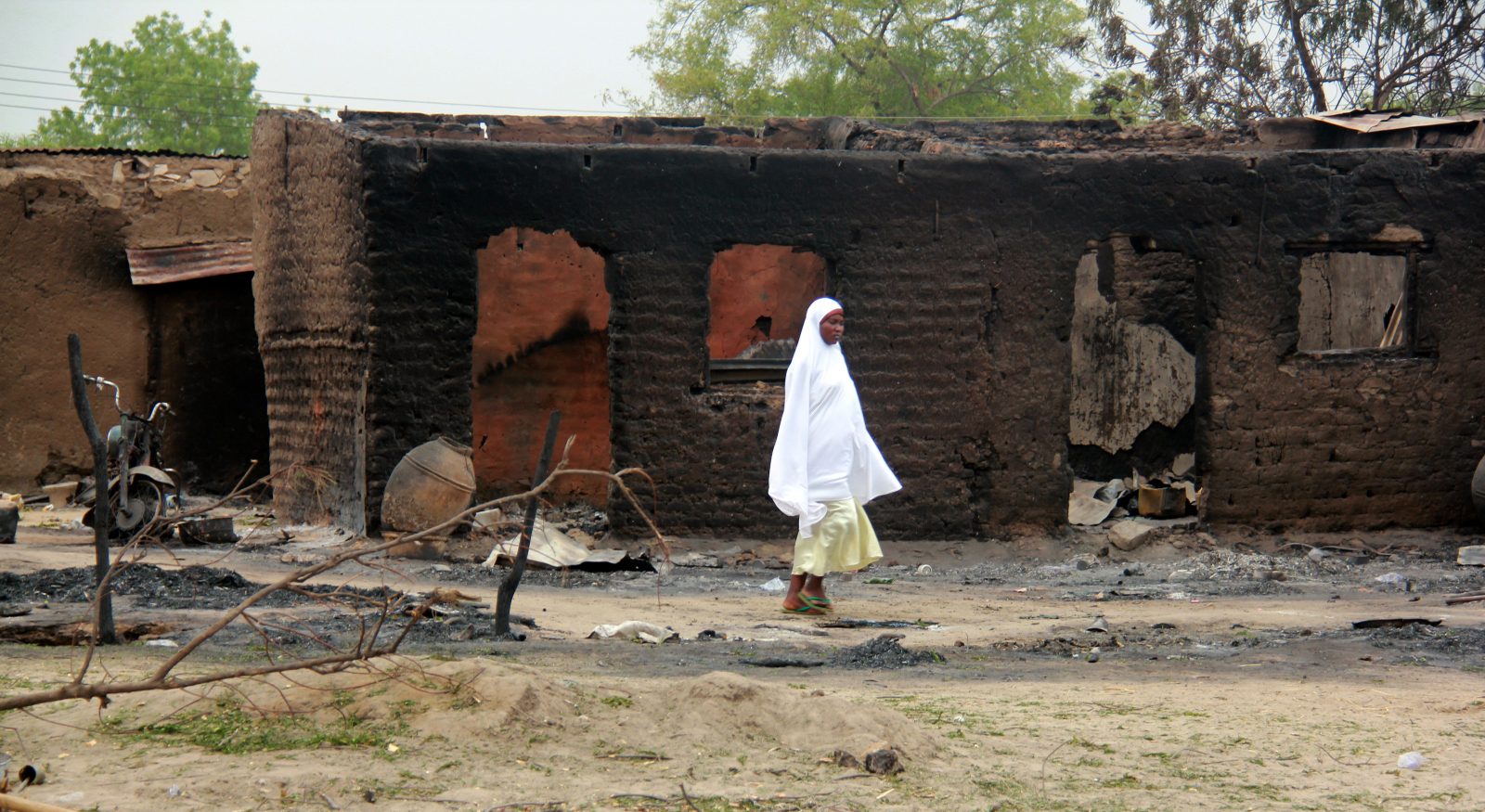 woman walking past burnt houses